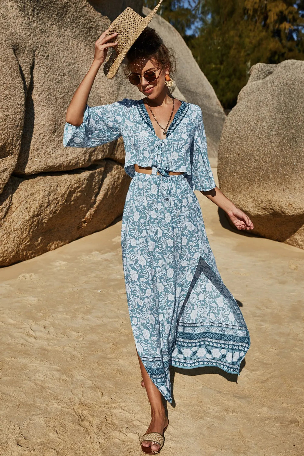 Woman wearing a blue printed half sleeve top and slit skirt set with floral patterns, beach background