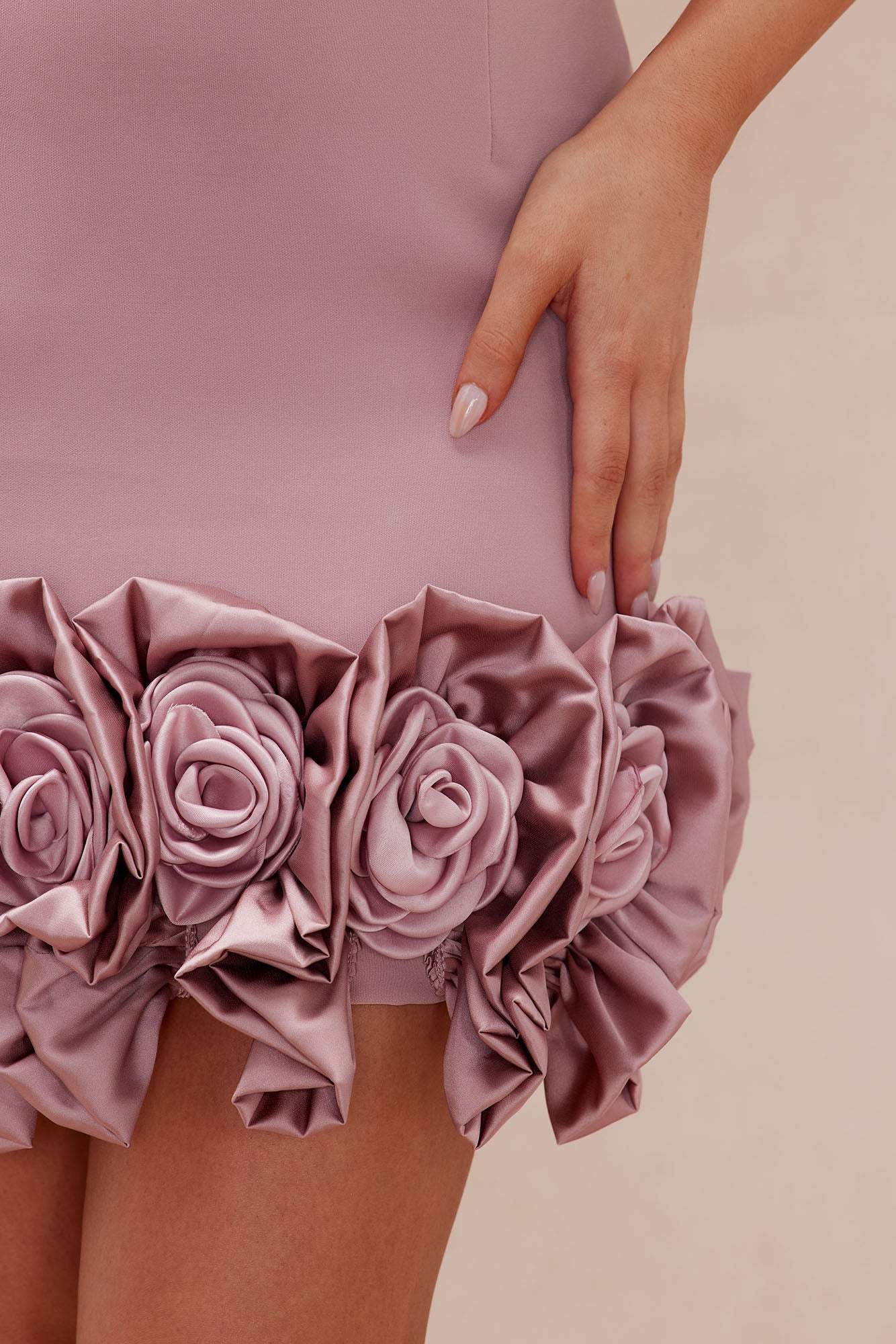 Close-up of Sasha Rose Hem Mini Dress in rose with floral hem detail and hand resting on skirt