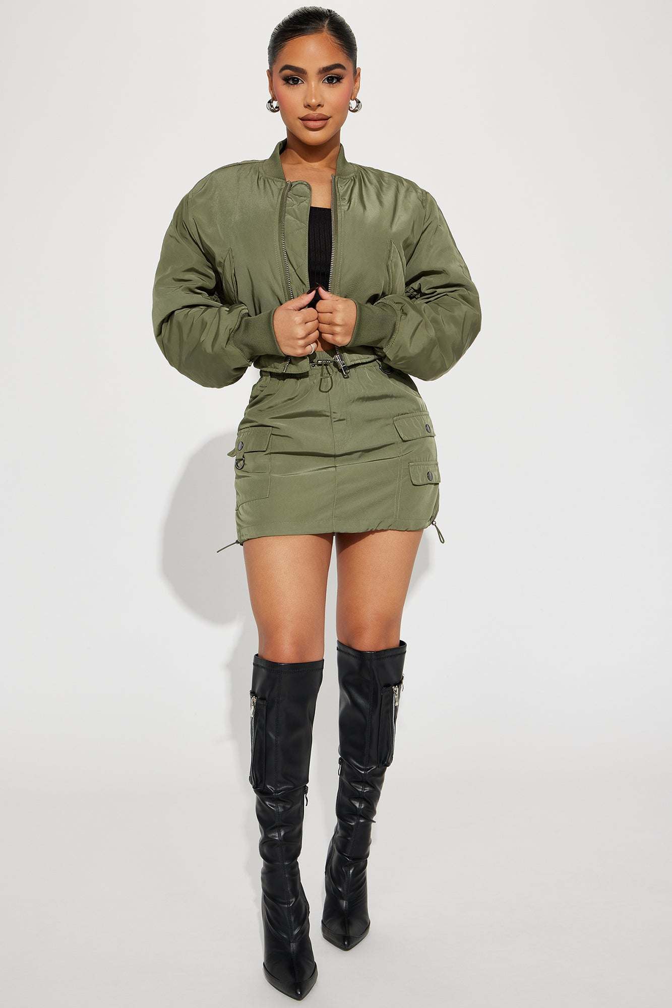 Olive bomber skirt set with cropped zip-up jacket and cargo pocket mini skirt styled with black knee-high boots