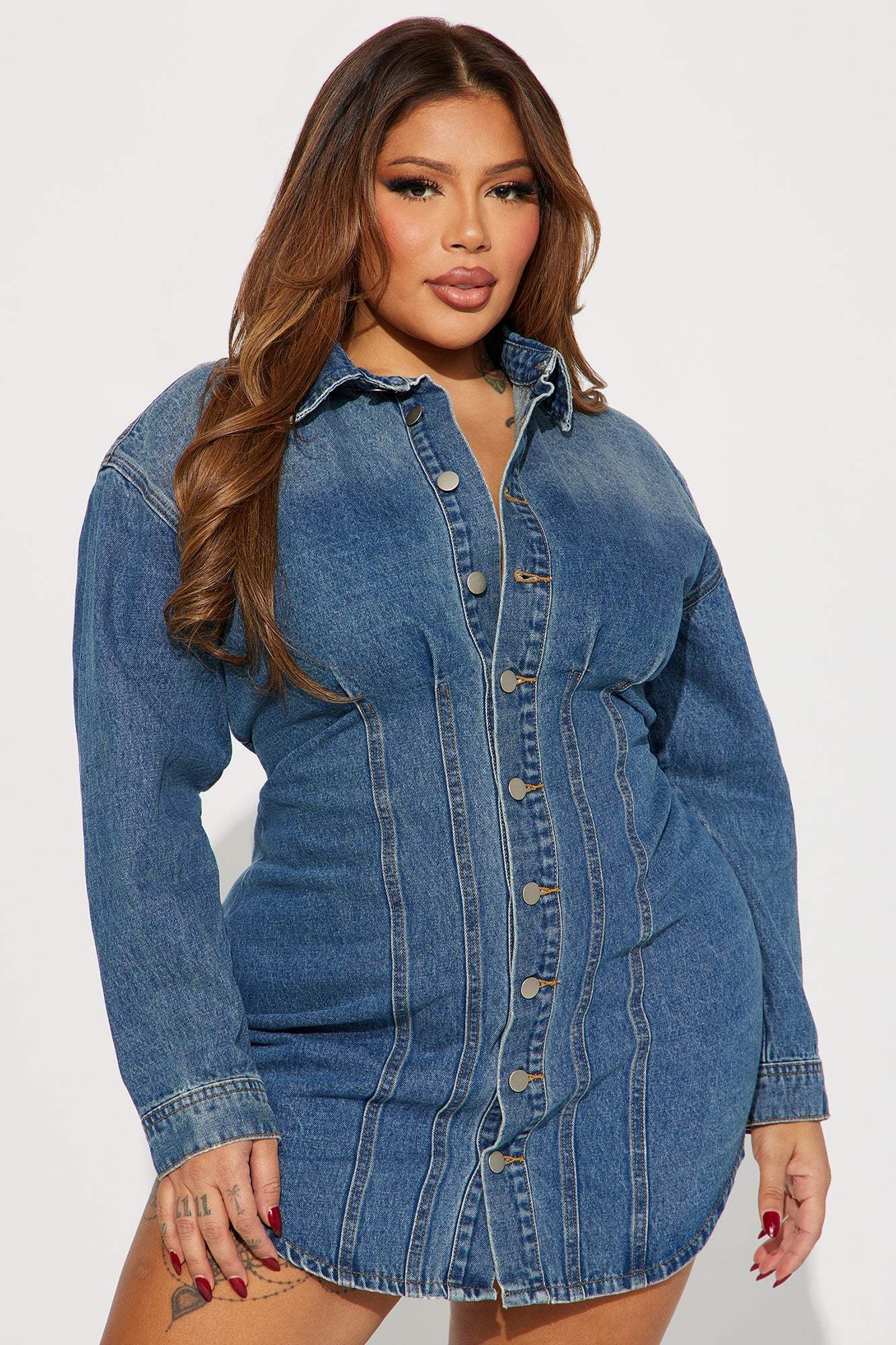 Plus size model wearing Alessandra Denim Mini Dress in medium wash with button front and long sleeves