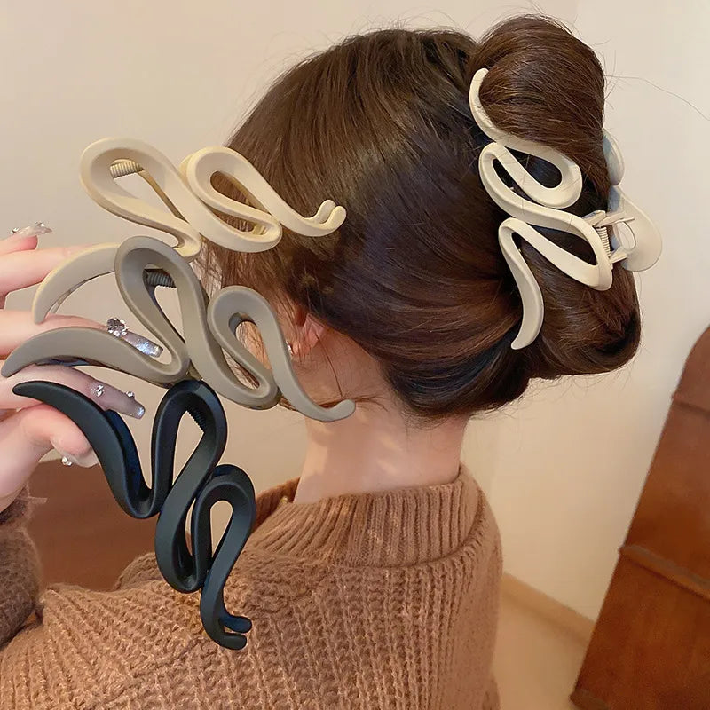 Alloy acrylic hair claw clip holding up bun hairstyle in beige and black colors