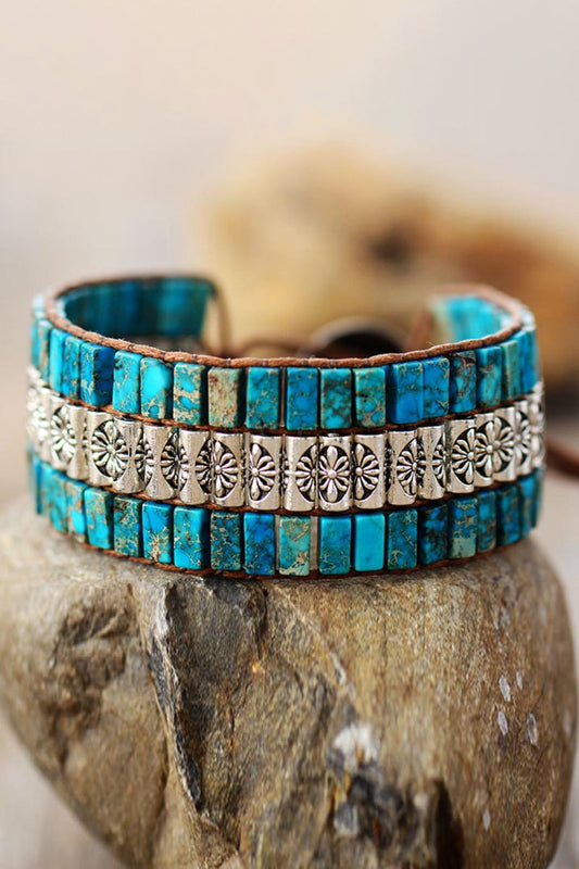 Handmade triple layer natural stone bracelet with turquoise stones and silver alloy accents on rock background