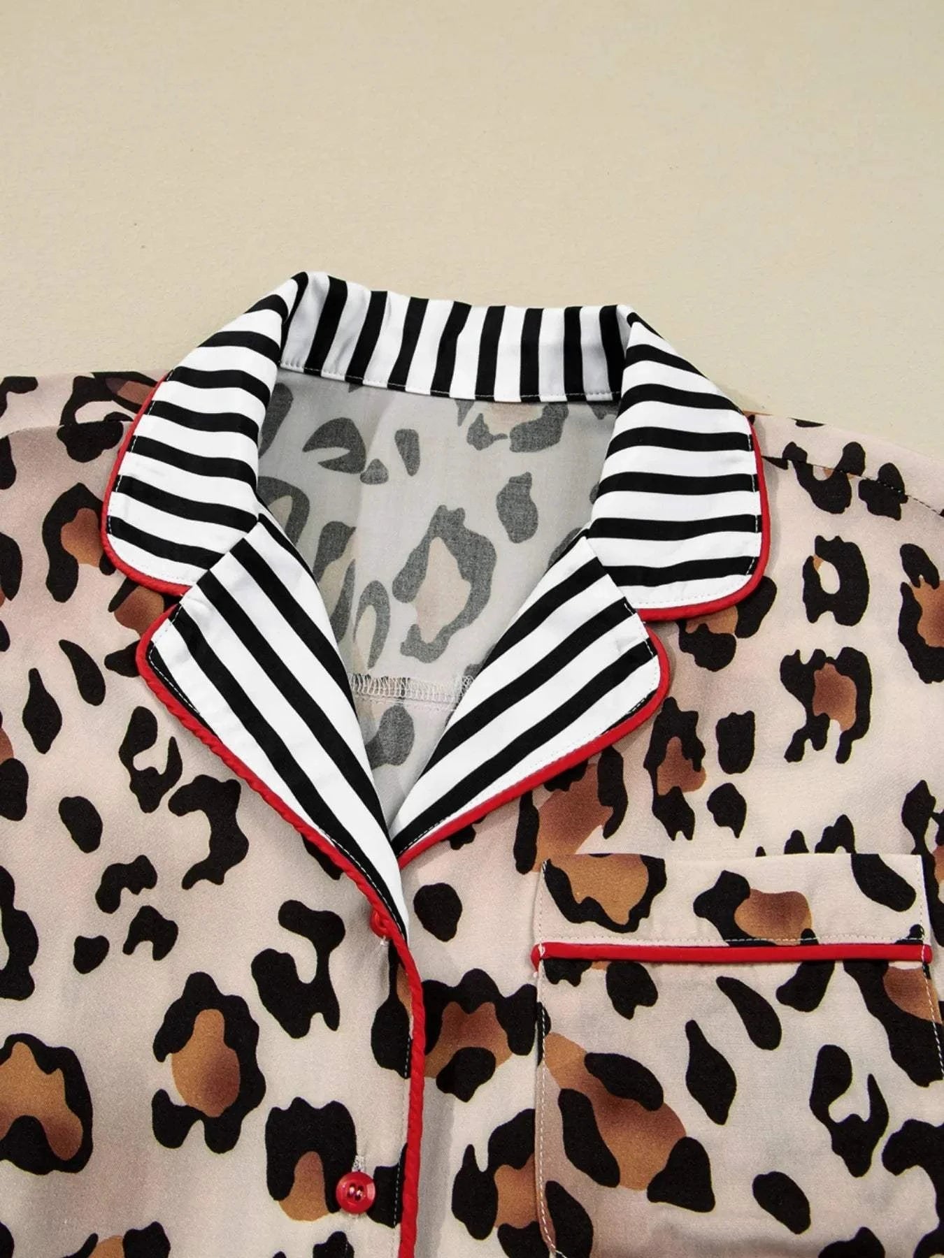 Close-up of leopard print shirt collar with black and white striped trim and red piping detail