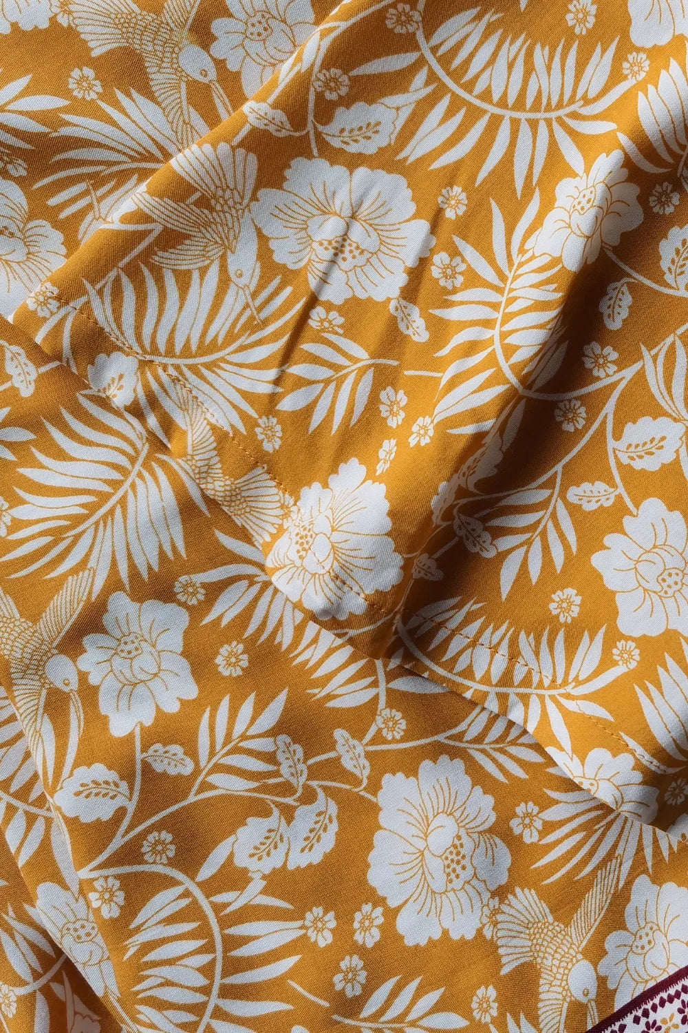 Close-up of mustard yellow printed fabric with white floral pattern for half sleeve top and slit skirt set