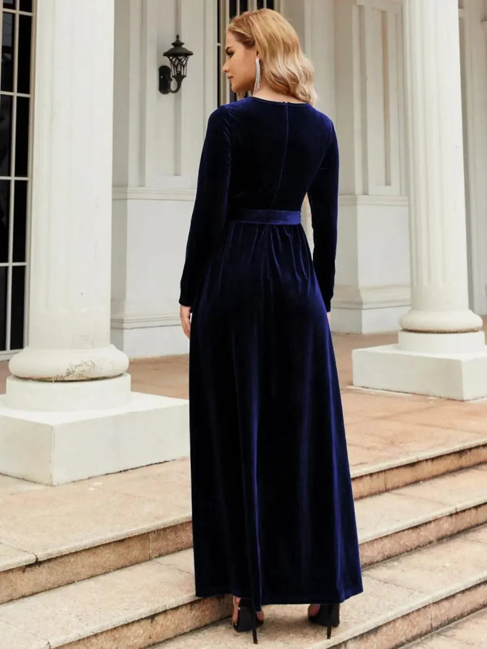 Woman wearing navy blue tie front long sleeve maxi dress with round neck standing on steps outdoors