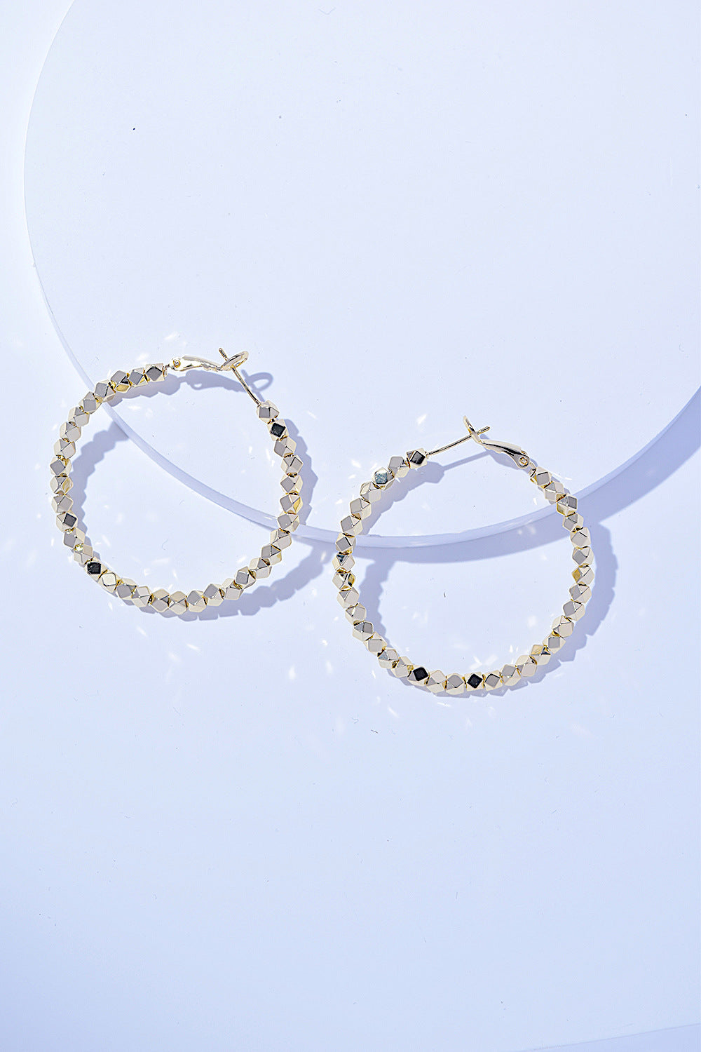 Pair of textured alloy hoop earrings with 2.4 inch length on white background