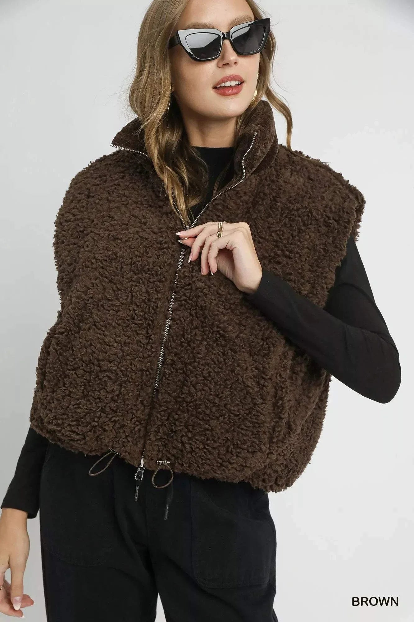 Woman wearing brown sherpa-lined zip vest with drawstring hem and pockets