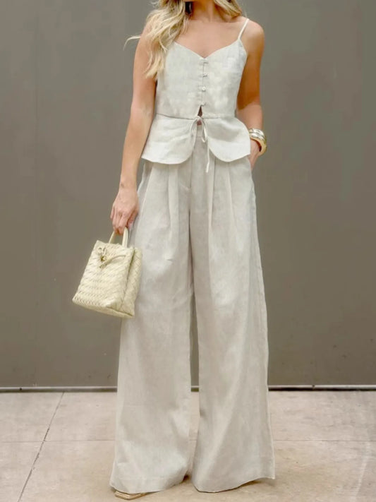 Woman wearing beige 100% cotton V-Neck Cami and Pants Set with buttoned tied top and wide-leg pants, holding woven handbag.