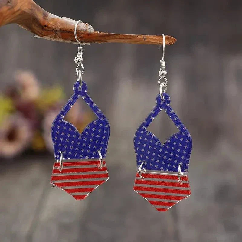 Pair of acrylic US flag earrings with star and stripe pattern hanging on a wooden branch