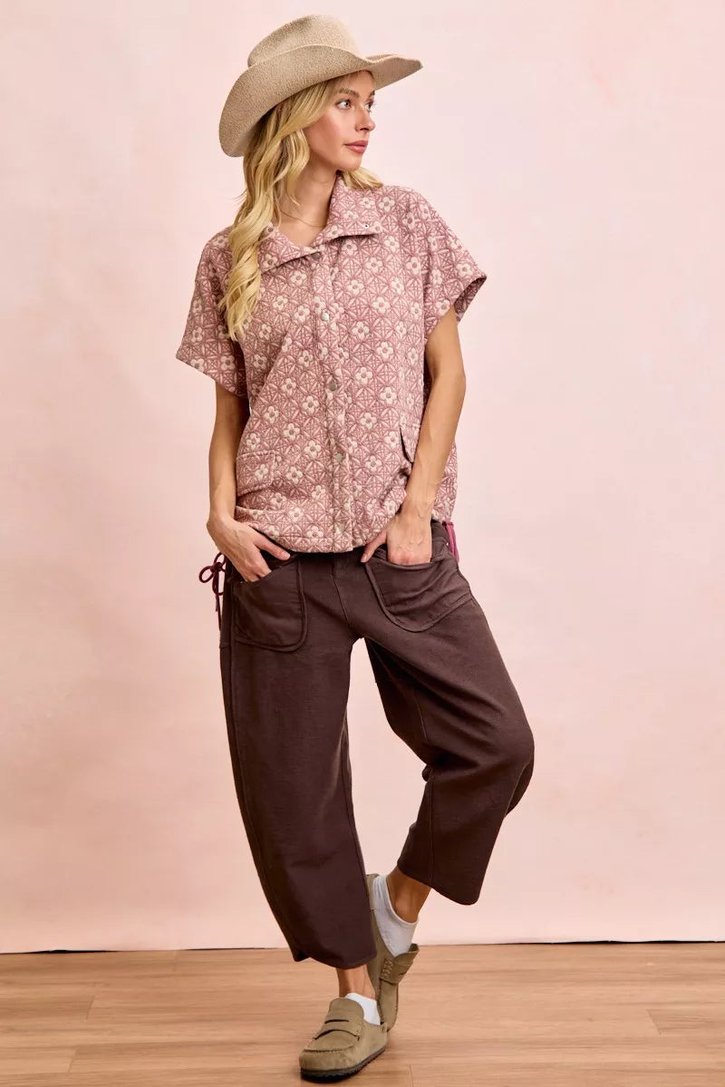 Woman wearing BiBi Washed Terry Pants with pockets in brown, paired with a floral shirt and hat.