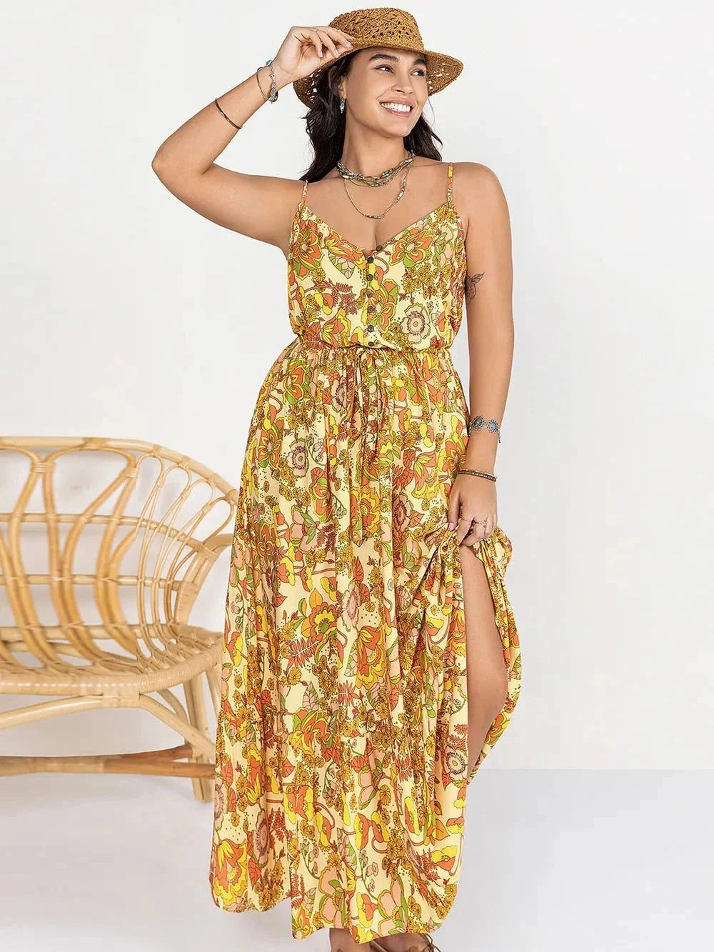 Plus size maxi dress with printed floral design, V-neck, cami straps, and a high slit worn by smiling woman with hat
