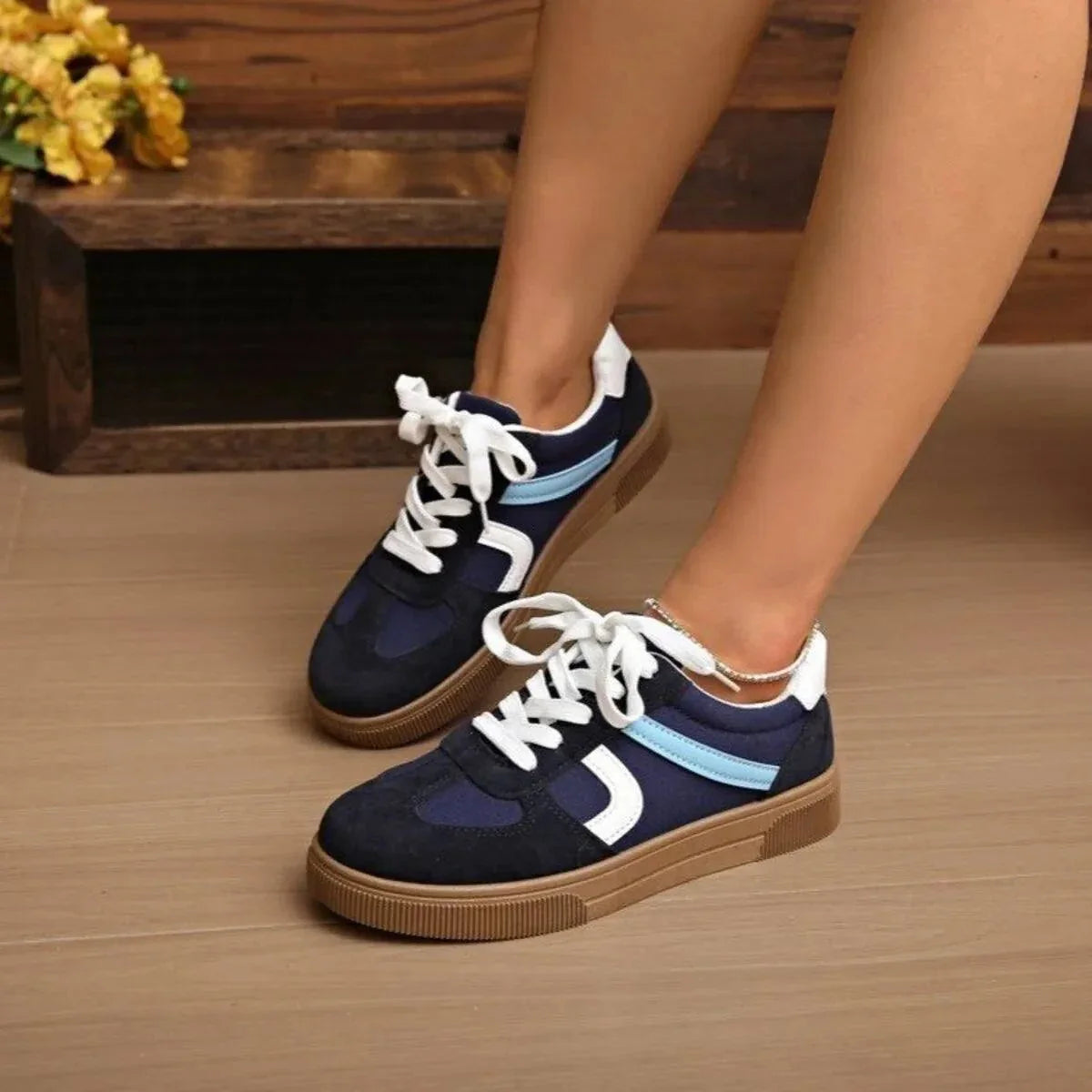 Navy blue and white lace up platform sneakers with rubber sole on feet indoors
