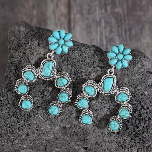Artificial turquoise alloy dangle earrings with floral and geometric design on rock background