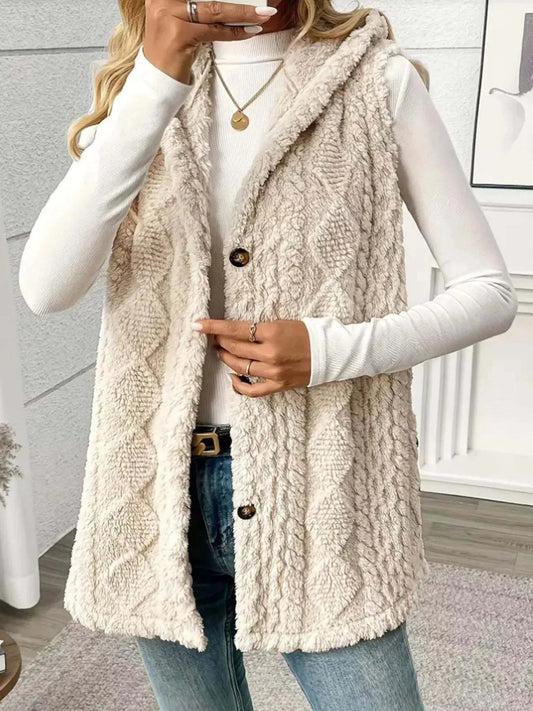 Beige button up plush hooded vest with textured knit pattern, sleeveless design, and front buttons worn over white long-sleeve top
