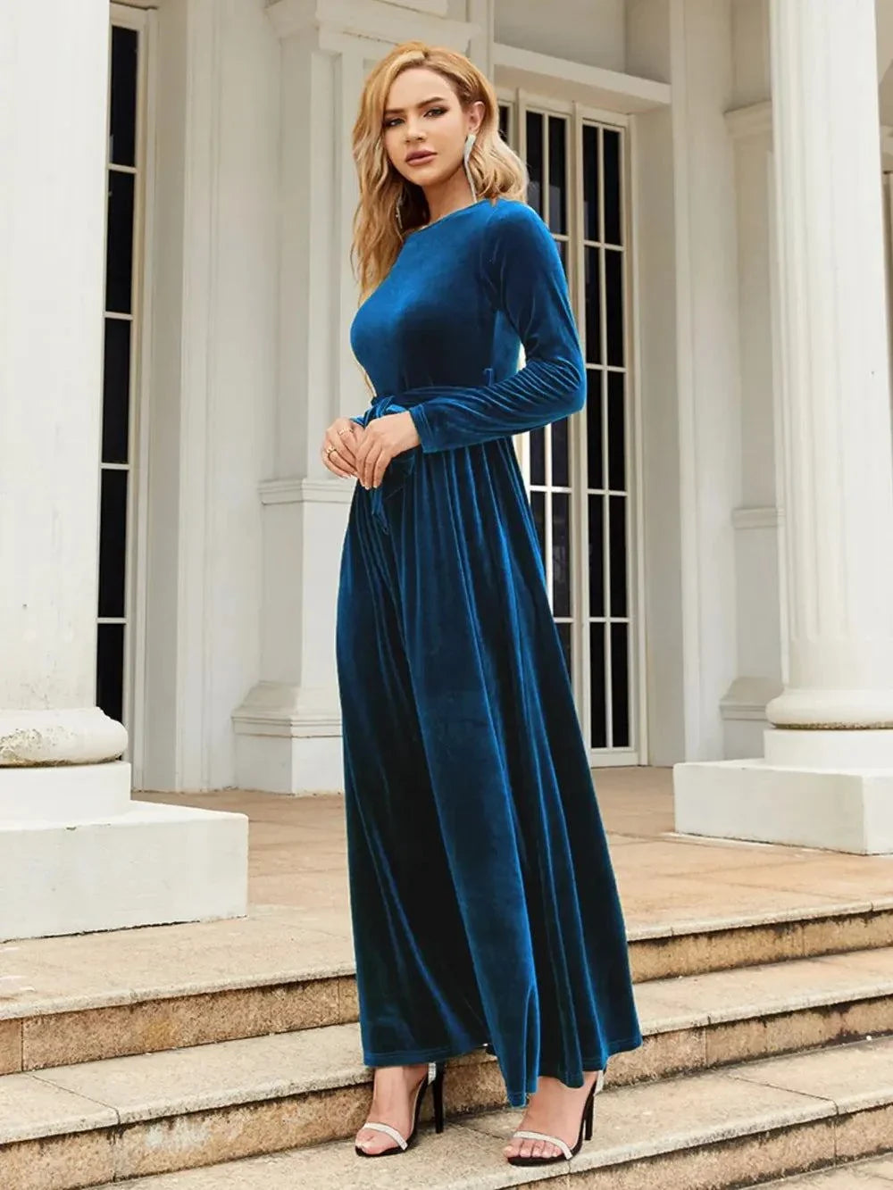 Woman wearing blue tie front round neck long sleeve maxi dress on outdoor steps