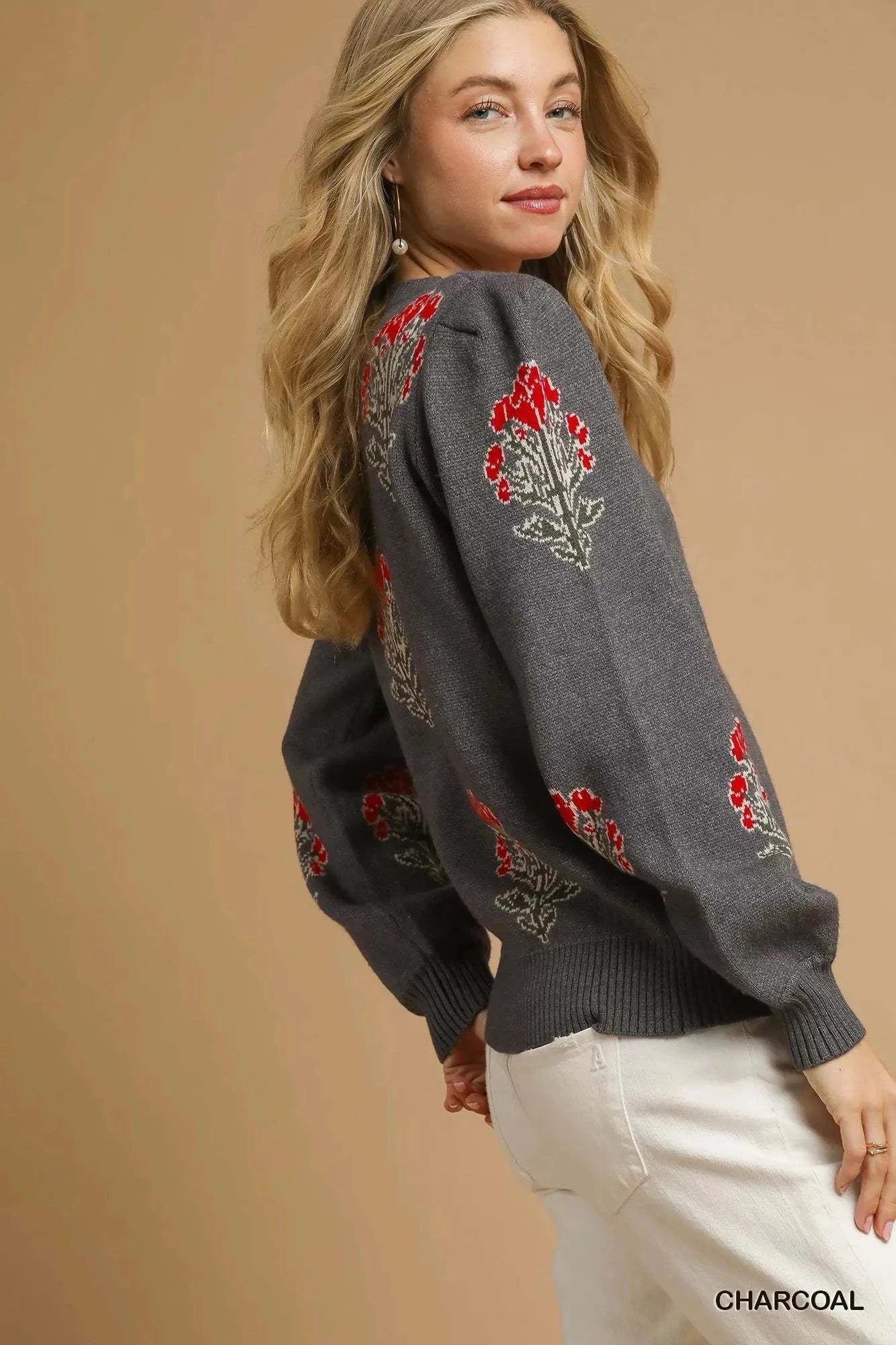Woman wearing charcoal Umgee Single Flower Stem jacquard sweater with red floral design and ribbed cuffs
