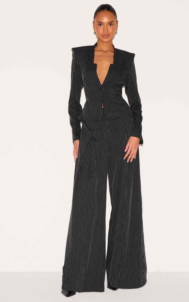 Woman wearing black pinstripe shirt detail straight leg jumpsuit with tailored woven fabric and long sleeves.