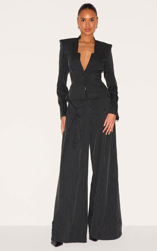 Woman wearing black pinstripe shirt detail straight leg jumpsuit with tailored woven fabric and long sleeves.