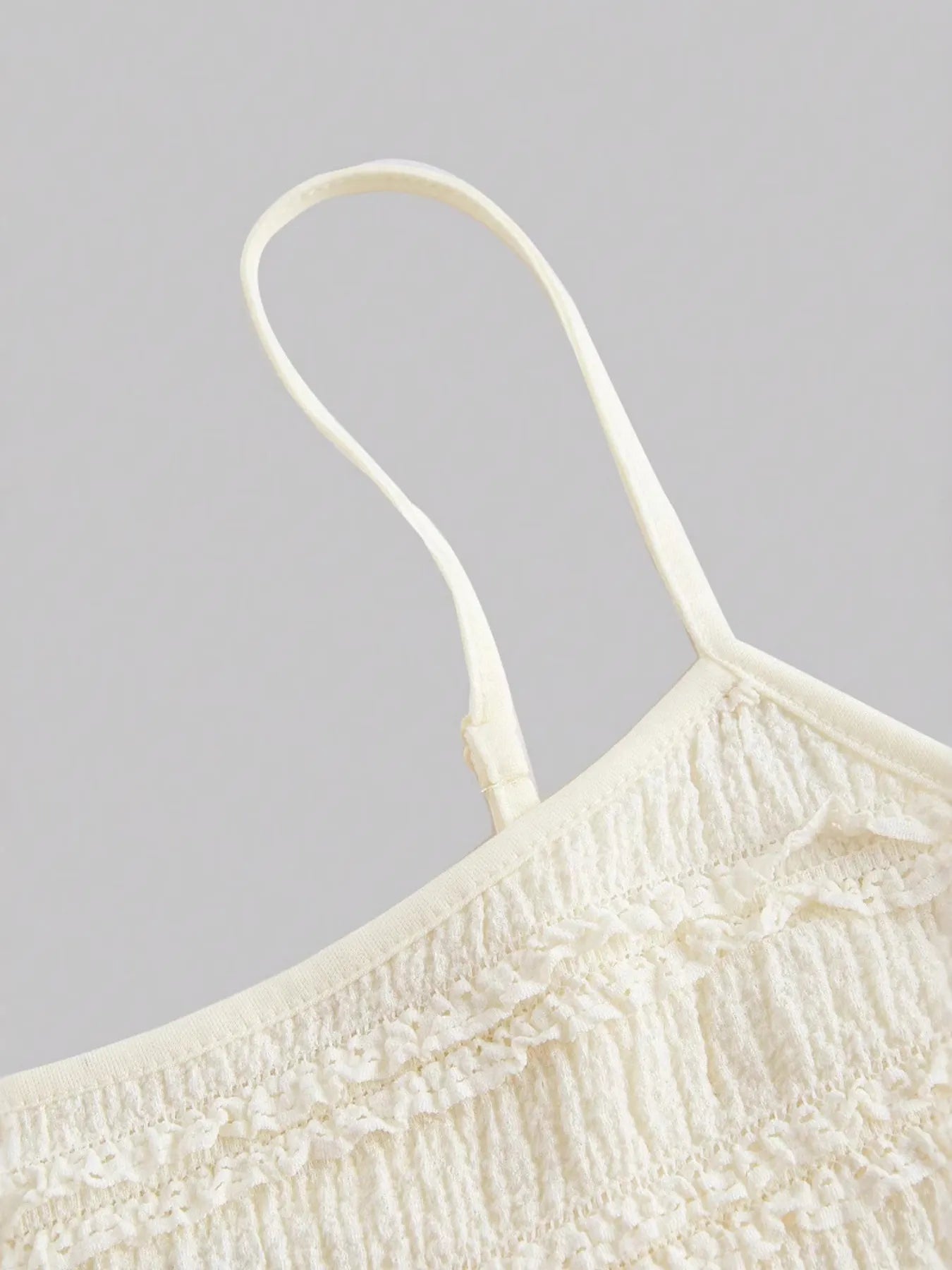 Close-up of white frill scoop neck cami with ruched, smocked detailing and thin straps