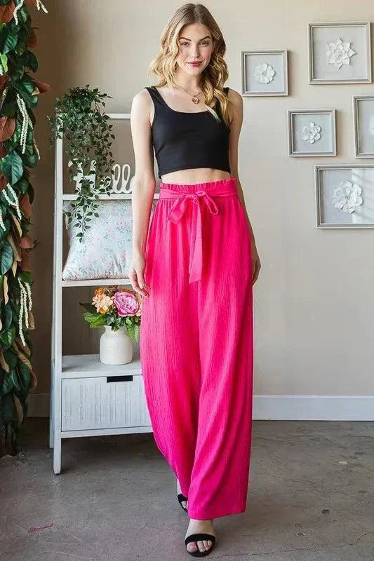 Plus size front tie pants with paperbag waistband in bright pink worn with black crop top and sandals