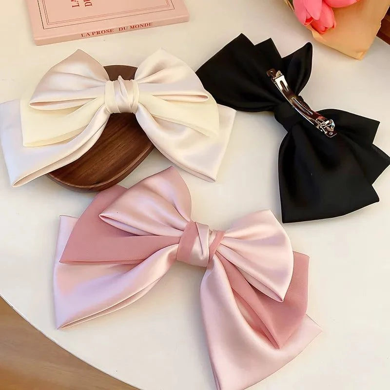 Three elegant bow cloth hair clips in white, black, and pink colors with metal alloy clips.