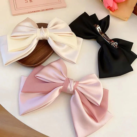 Three elegant bow cloth hair clips in white, black, and pink colors with metal alloy clips.