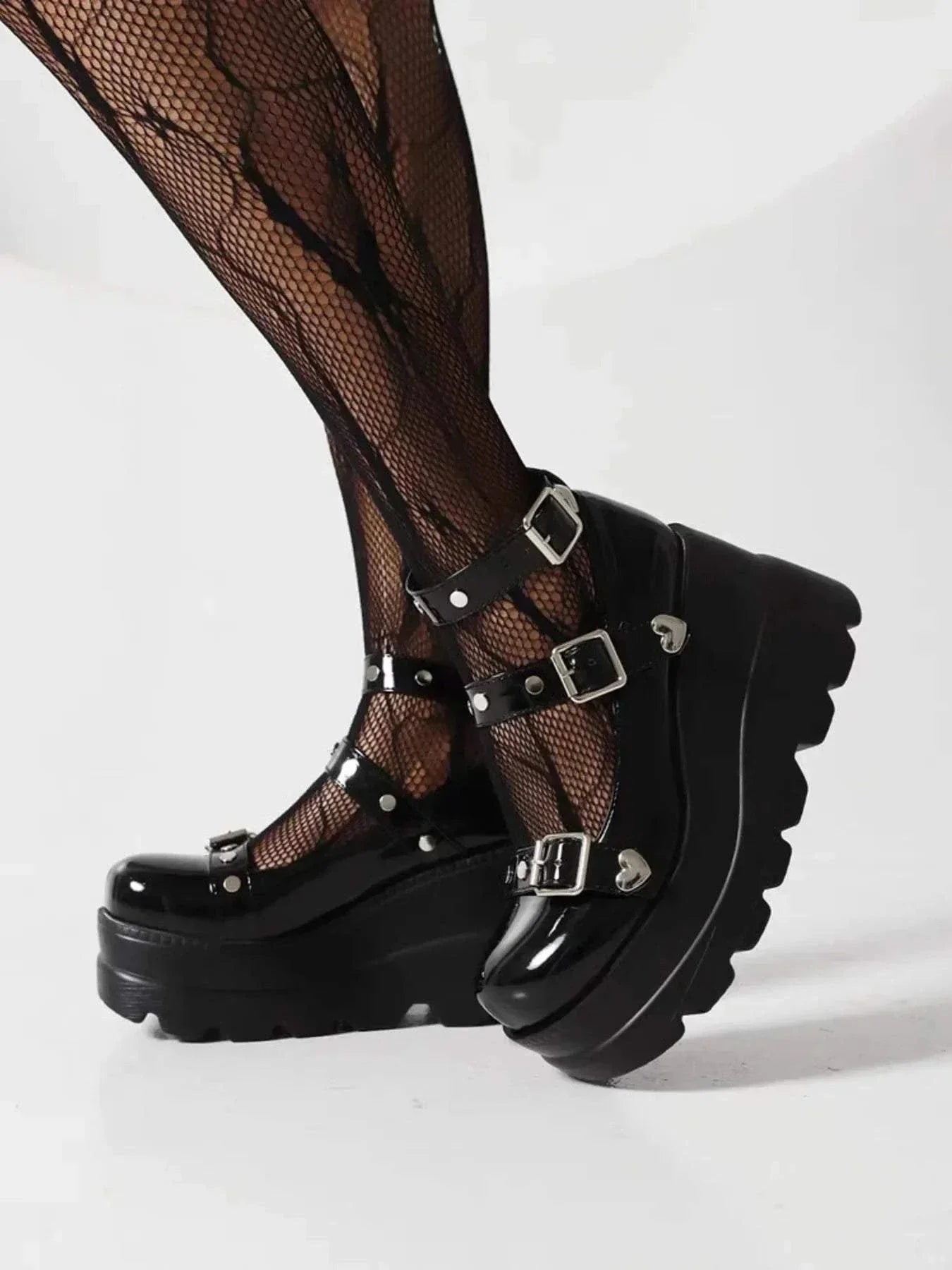 Black platform Mary Jane shoes with triple buckle straps and chunky sole worn with fishnet tights