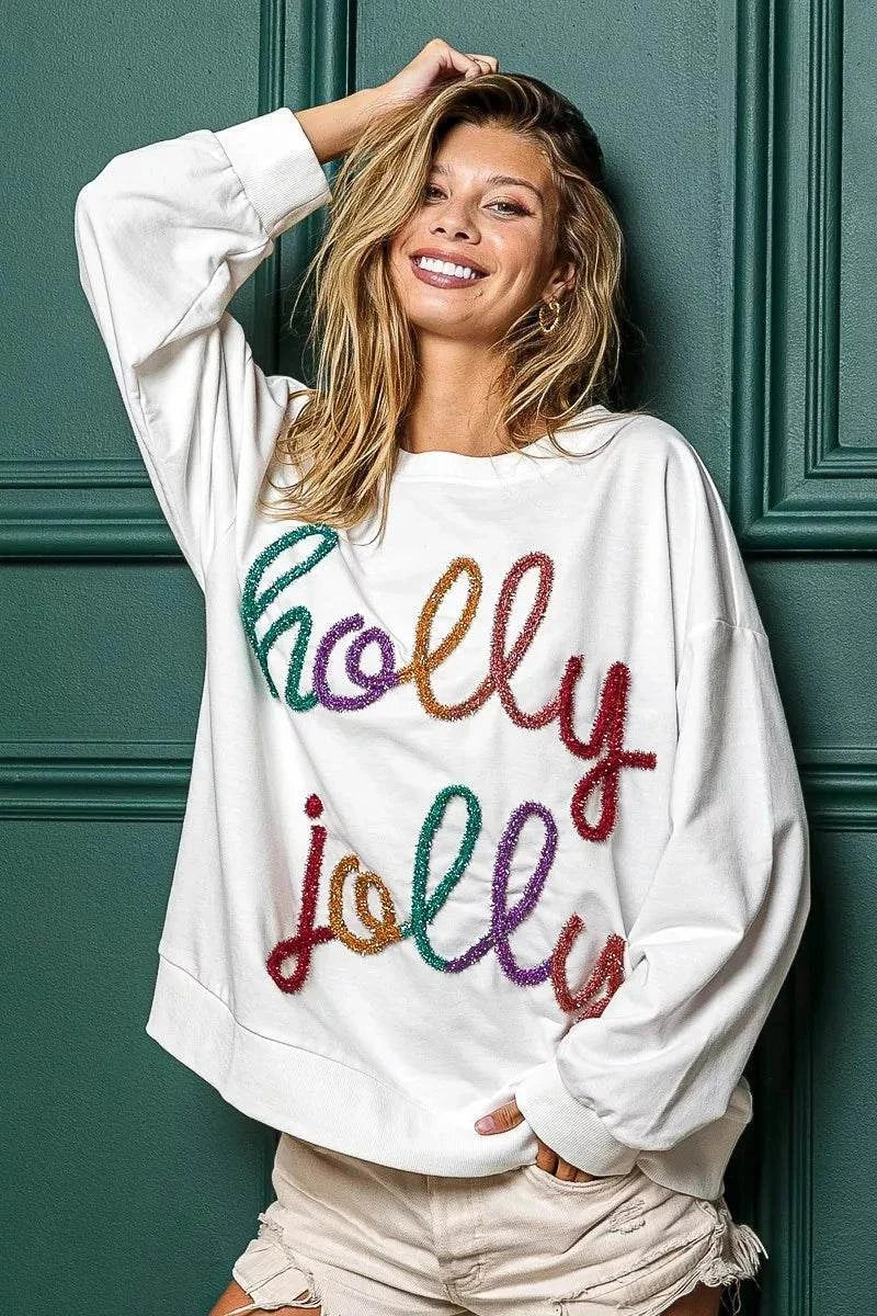 Woman wearing oversized white Holly Jolly Christmas French Terry Sweatshirt with colorful festive text design