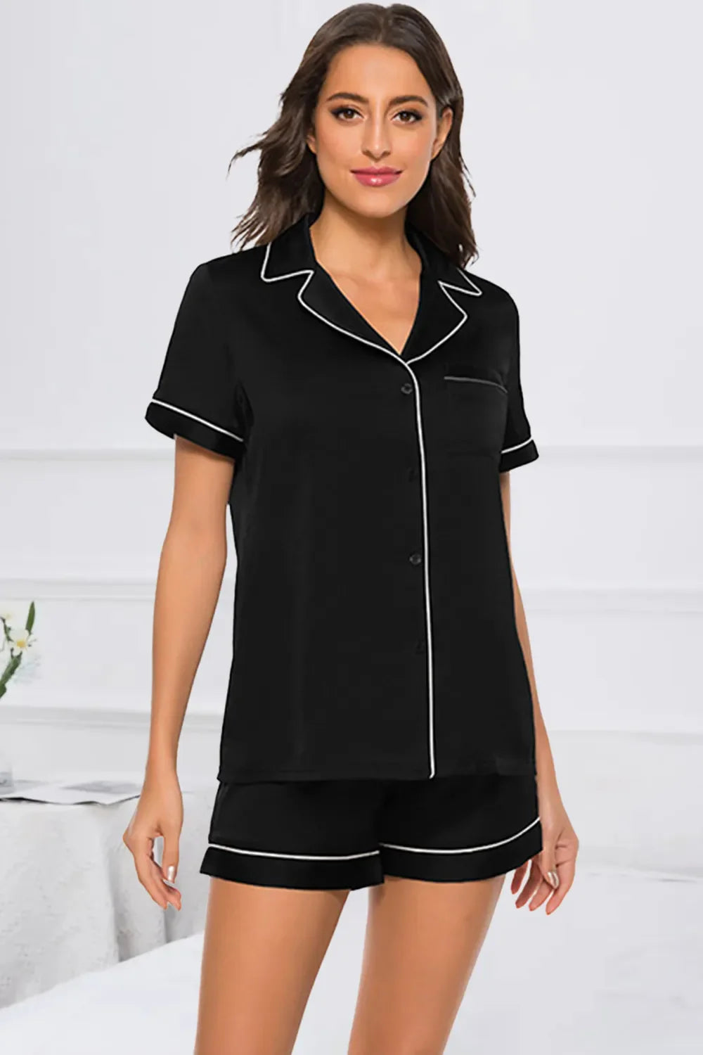 woman wearing black printed button up short sleeve top and shorts lounge set with white piping trim