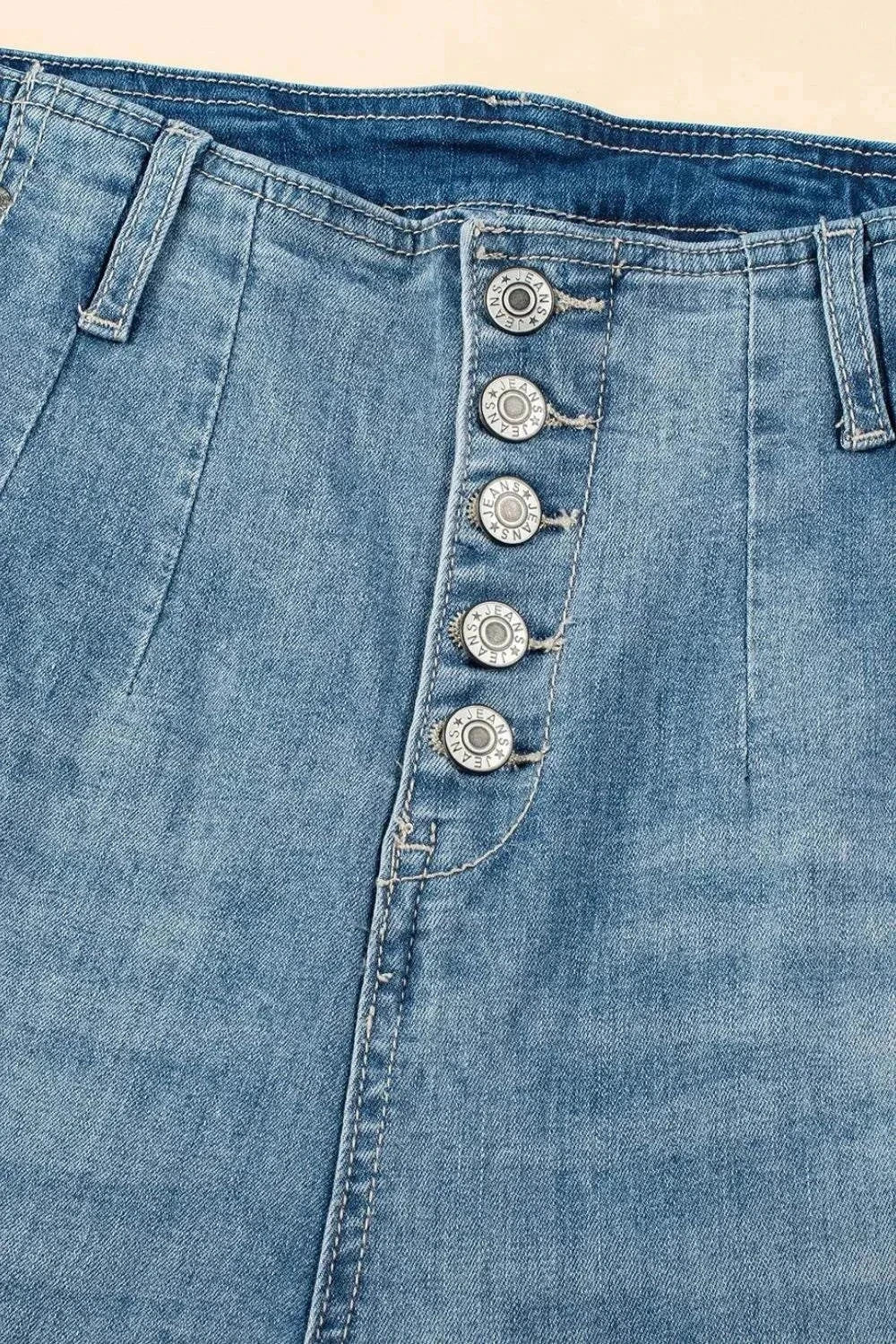 Close-up of blue denim button fly high waist jeans with five silver buttons and belt loops