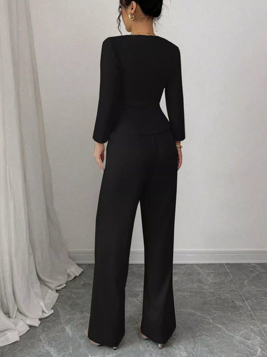 Woman wearing black button up long sleeve top and pants set standing indoors with back facing camera