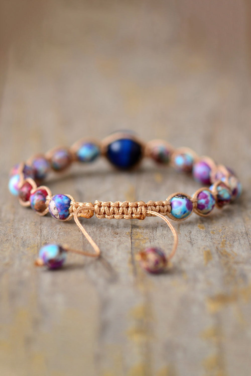 Imperial Jasper natural stone beaded bracelet with adjustable woven cord and multicolored round beads on wooden surface