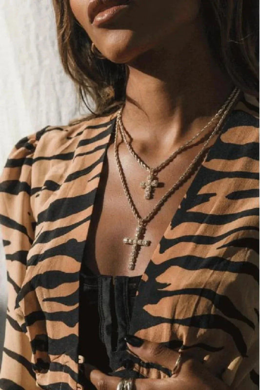 Woman wearing layered brass inlaid zircon cross pendant necklaces with gold-plated chains