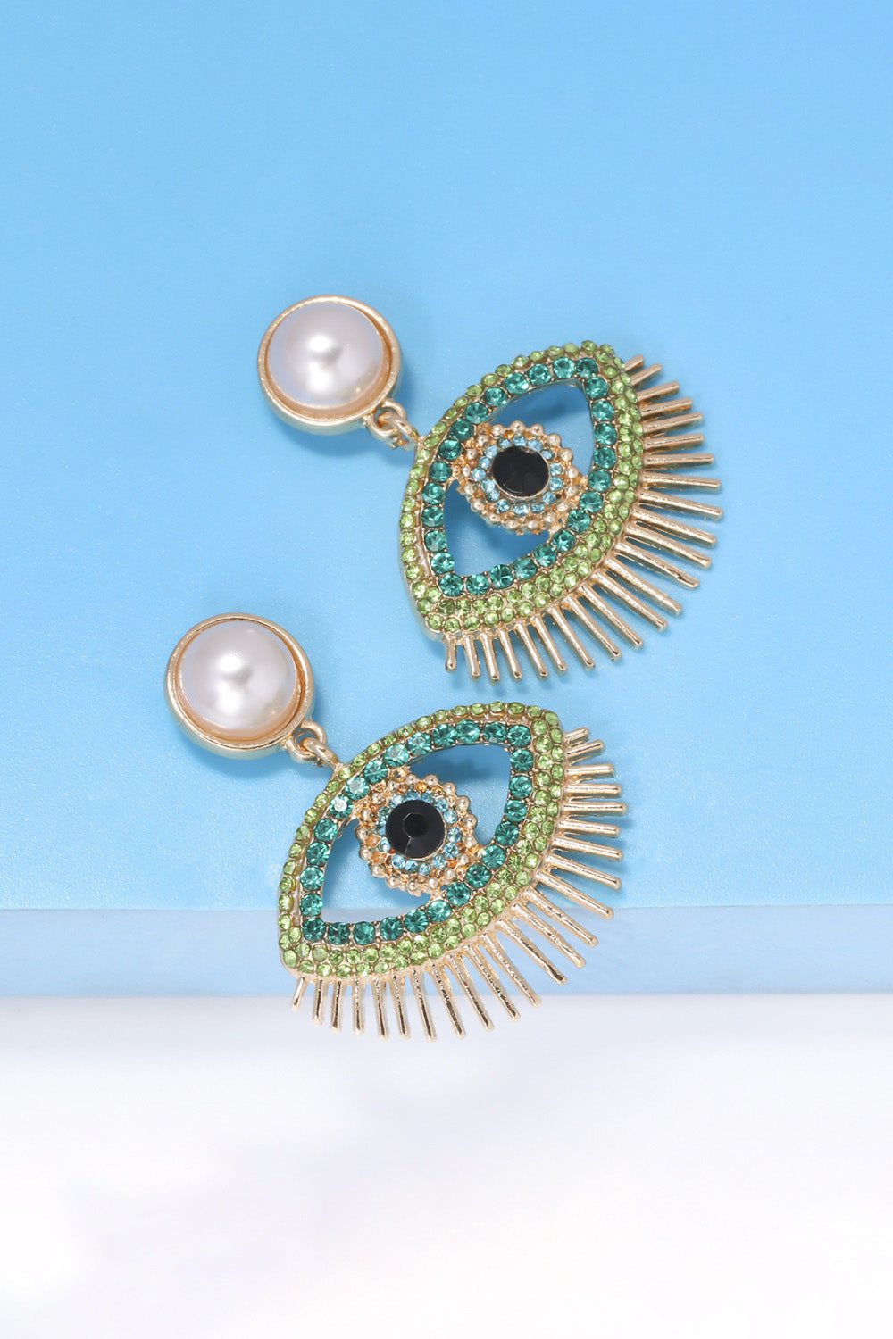 Evil Eye Shape Rhinestone dangle earrings with synthetic pearl and zinc alloy on blue background