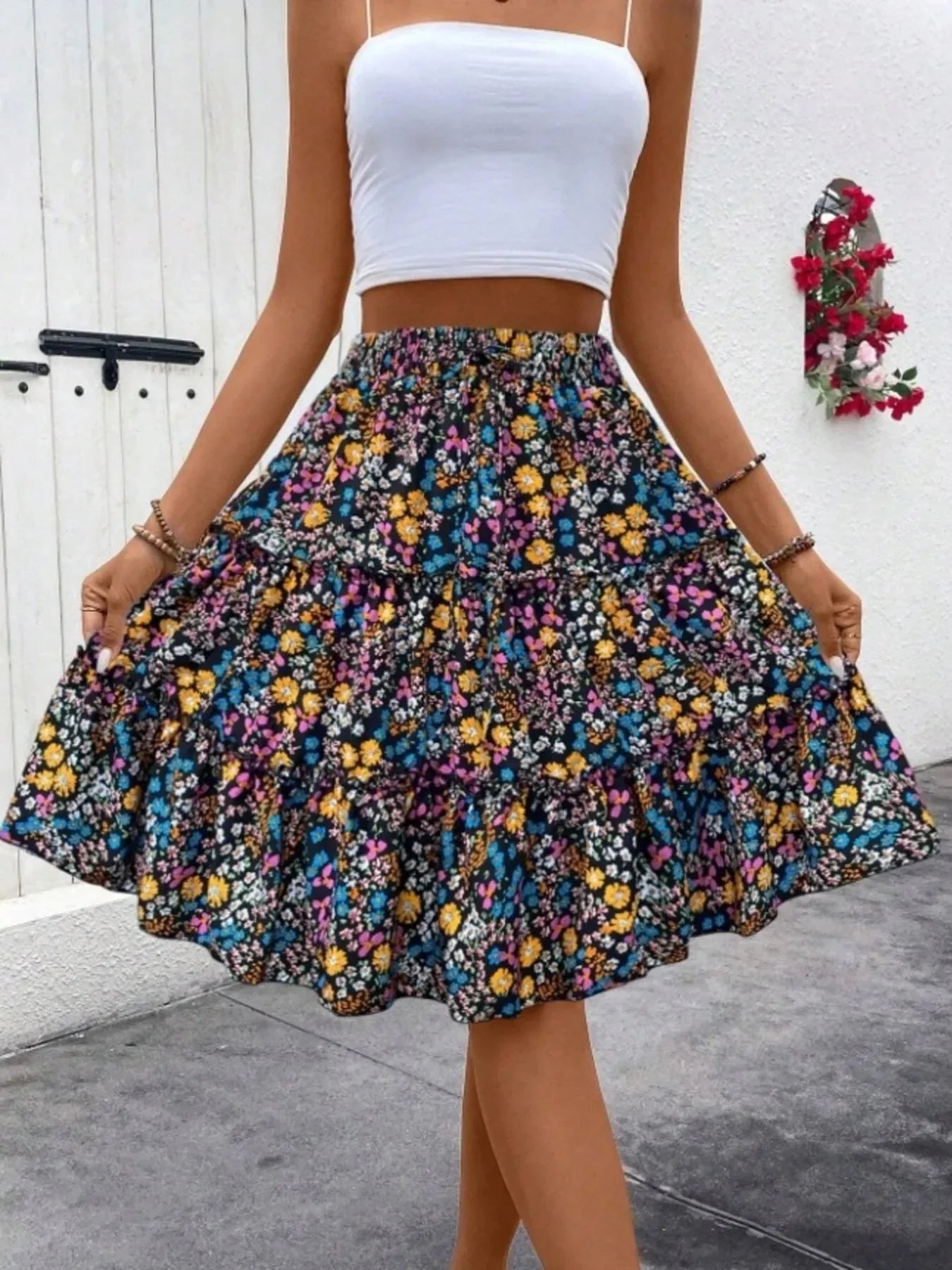 woman wearing floral print midi skirt and white crop top standing outdoors