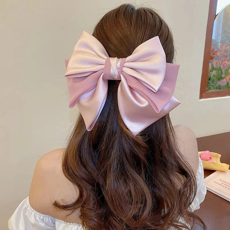 Pink and lavender bow cloth hair clip securing long brown hair from behind