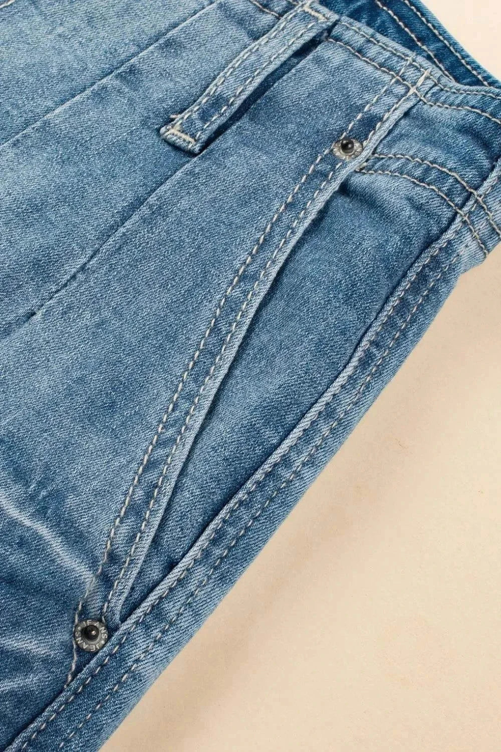 Close-up of blue button fly high waist jeans pocket and stitching detail