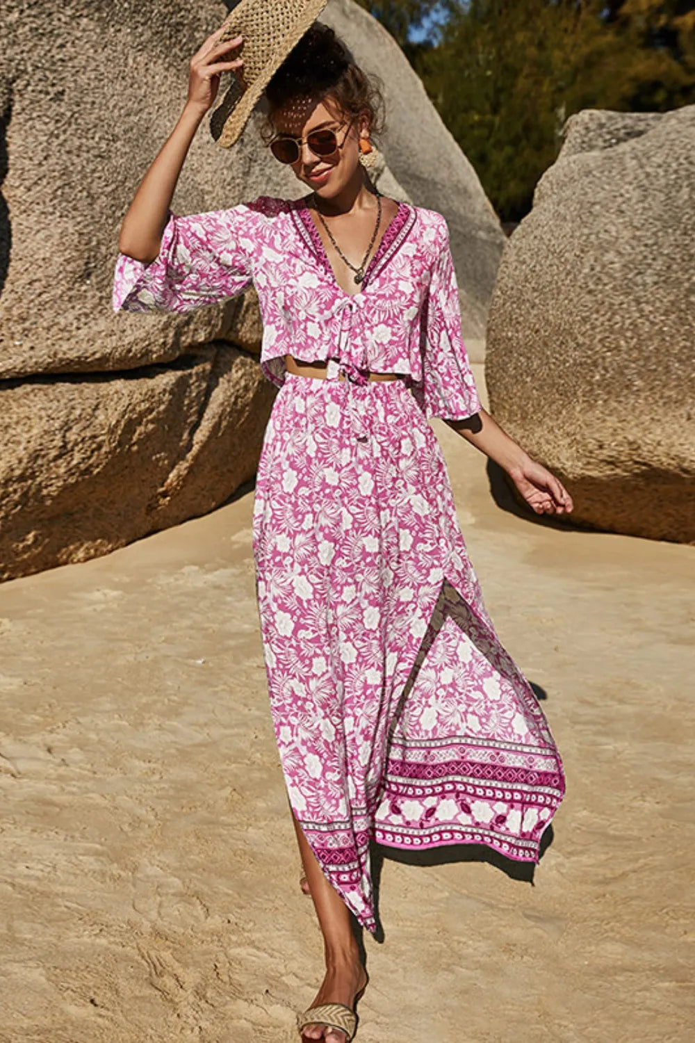 Woman wearing pink floral printed half sleeve top and slit skirt set on a sandy beach