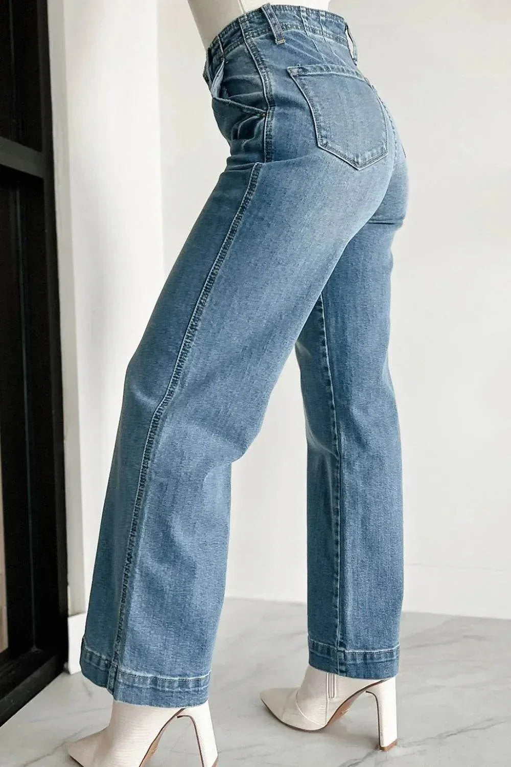 Side view of button fly high waist jeans worn with white heeled boots