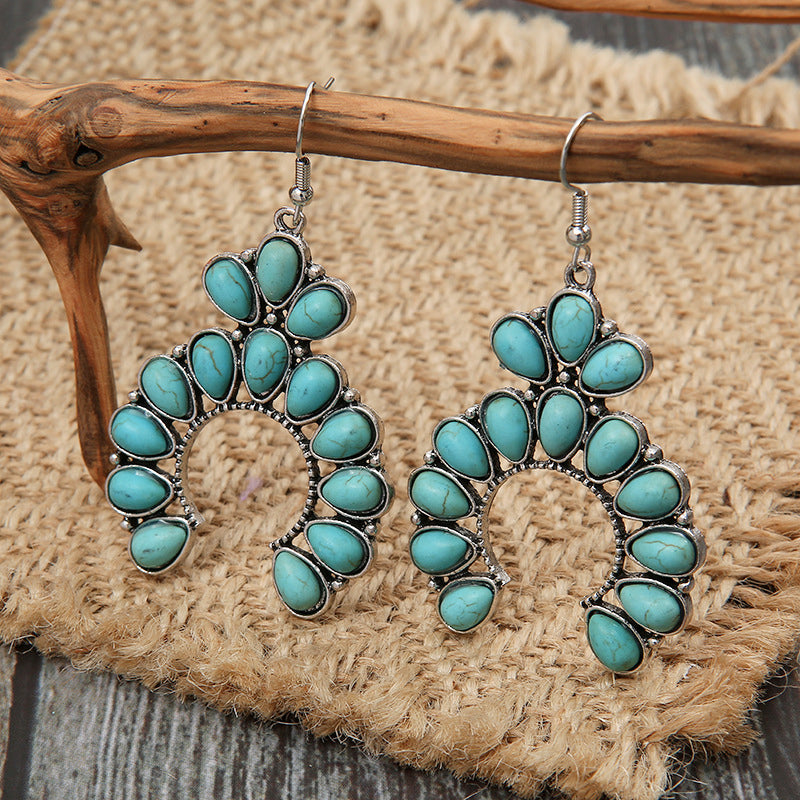 Elegant artificial turquoise drop earrings with silver settings on rustic wooden display