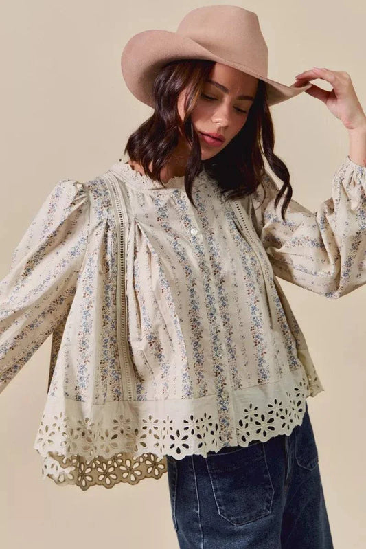 Woman wearing a floral print lace button-down shirt with ruffled eyelet hem and long puff sleeves