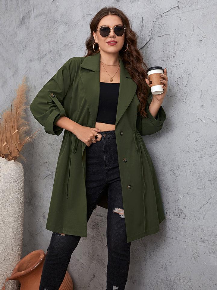 plus size trench coat with lapel collar and roll-tab sleeves in olive green worn by woman with sunglasses holding coffee cup