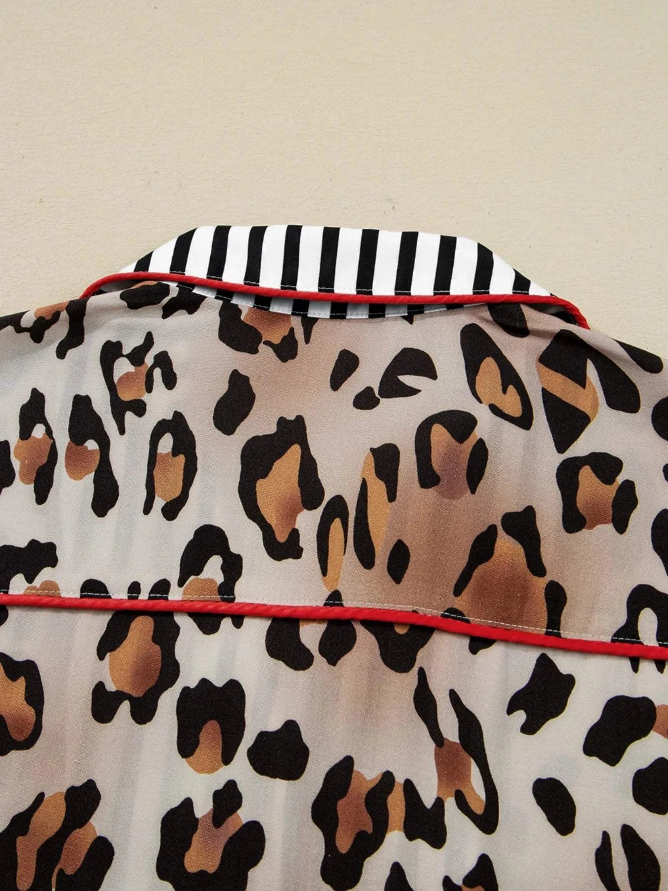 Leopard print shirt with black and white striped trim and red piping detail