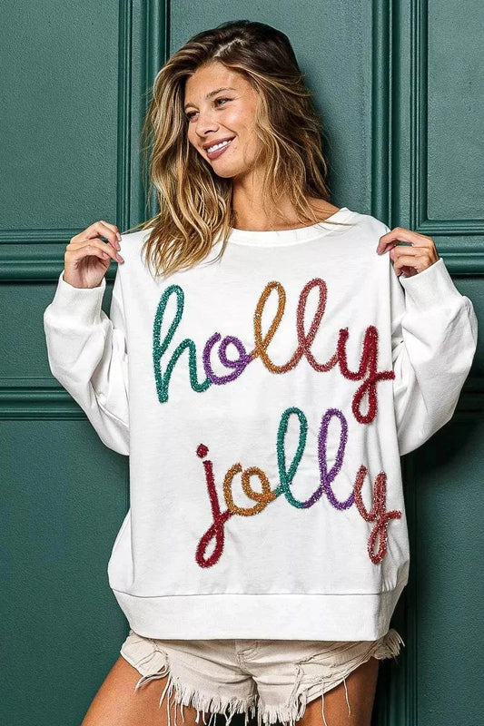 Woman wearing oversized white Holly Jolly Christmas French Terry Sweatshirt with colorful festive text design.