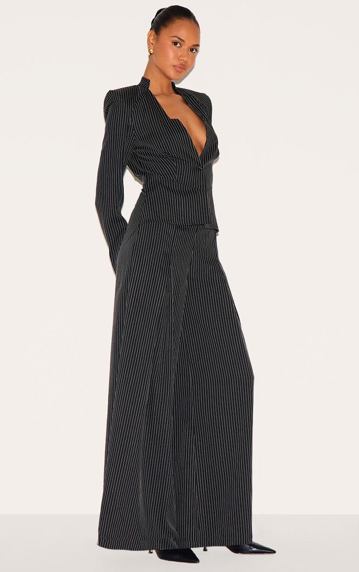 Woman wearing black pinstripe shirt detail straight leg tailored jumpsuit with long sleeves and shirt neckline.