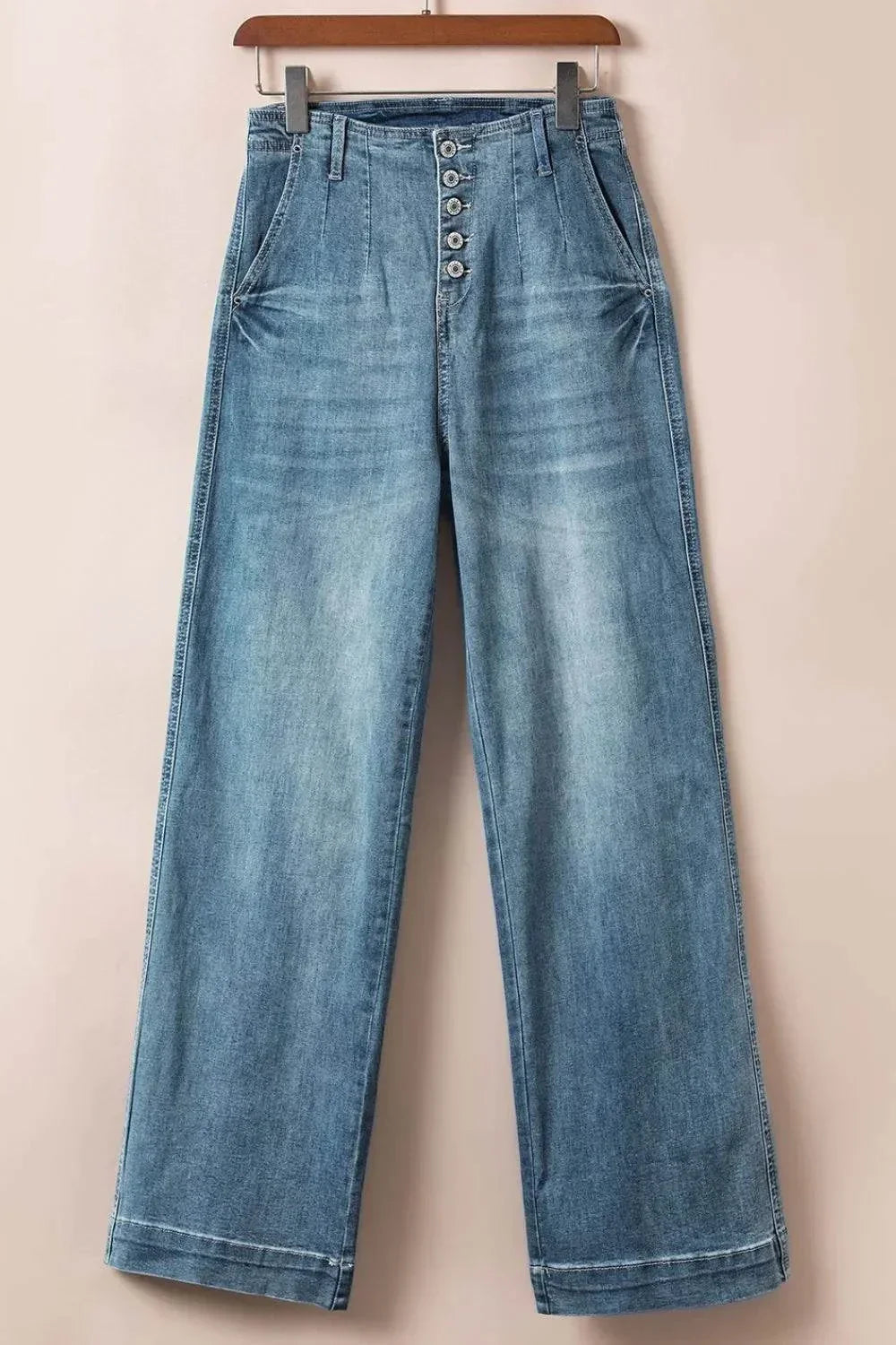 Light blue button fly high waist jeans with wide legs hanging on a wooden hanger
